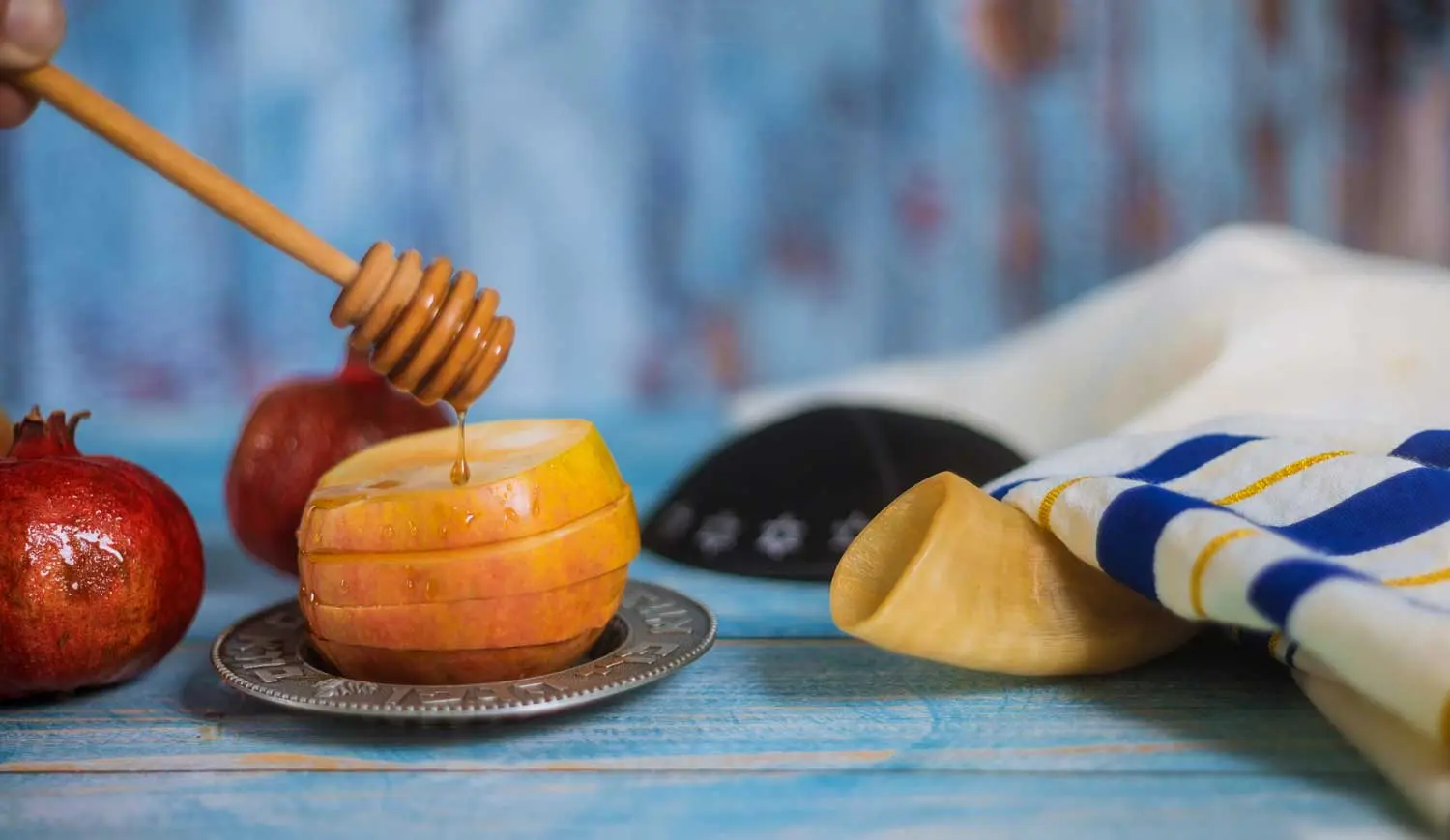 A honey stick with honey dripping onto a sliced apple.